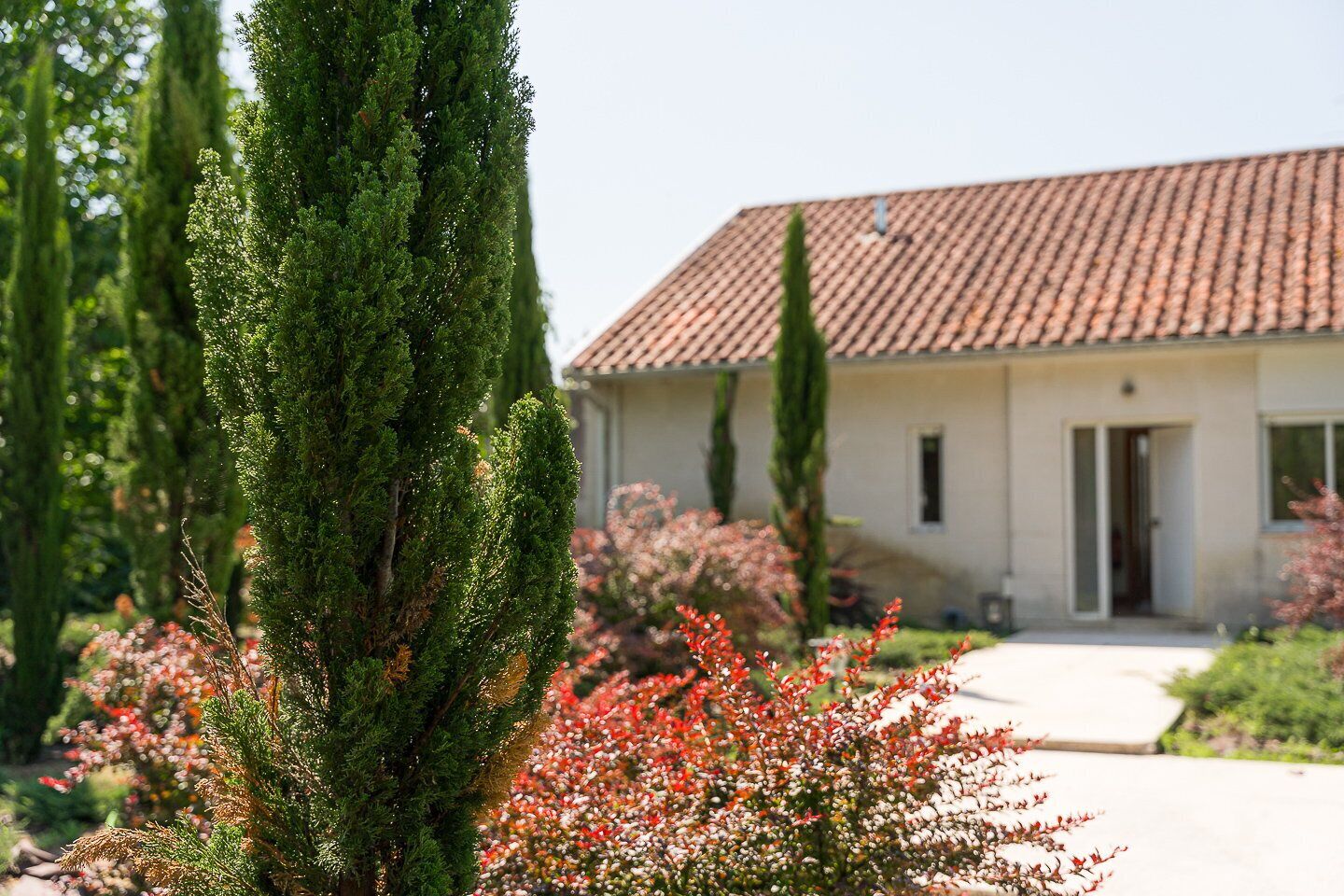 A building with a tiled roof, a door, and a pathway leading to the entrance.