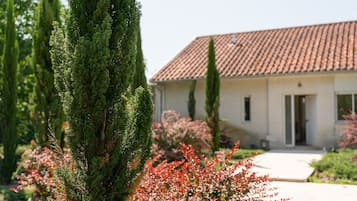 A building with a tiled roof, a door, and a pathway leading to the entrance.