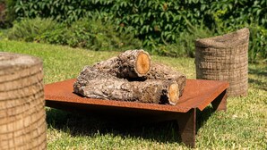 A rustic outdoor seating area with a wooden log and a metal table. - GuestReady - Quinta do Outeiro (Anadia)
