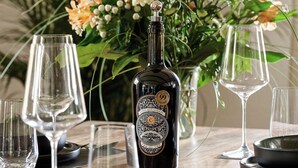 A table set with wine glasses, a bottle, and a floral arrangement.