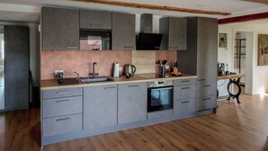 A modern kitchen with grey cabinets, a wooden countertop, and a built-in oven.
