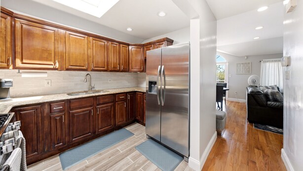 Una cocina moderna con armarios de madera, un refrigerador de acero inoxidable y un tragaluz.