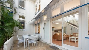 A modern house with a patio, a dining area, and a living room with a staircase. - Welcome to Caversham Townhouse (Arcadia)