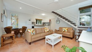 A living room with a sofa set, a coffee table, wicker chairs, a dining table, and a kitchen in the background. - Welcome to Caversham Townhouse (Arcadia)