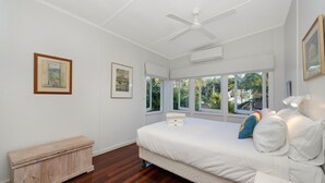 A bedroom with a bed, a ceiling fan, large windows, and a wooden bench. - Welcome to Caversham Townhouse (Arcadia)