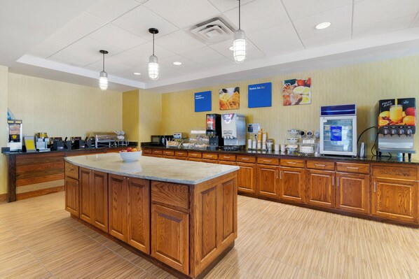 A hotel kitchen with a central island, wooden cabinets, and various appliances.