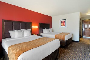 A hotel room with two beds, a red accent wall, and a patterned carpet. - Legend Hotel Minot (Minot)