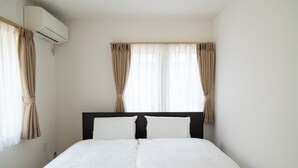 Een hotelkamer met een bed, gordijnen, een airconditioning en een raam.
