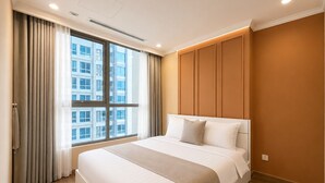 Ett hotellrum med en stor säng, ett fönster med gardiner, ett trägolv och en väggpanel.