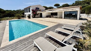 Ett modernt hus med en swimmingpool, utomhusmöbler och en uteplats.