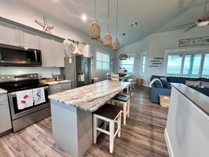 A modern kitchen with a central island, stainless steel appliances, and a dining area with a view.
