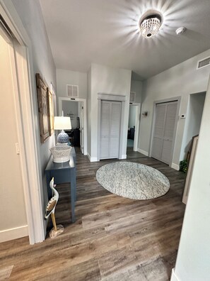 A hallway with wooden flooring, a round rug, and closed doors.