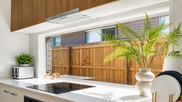 A modern kitchen with a large window, wooden fence outside, and a plant on the counter. - Haus Verde | 4BR Greenbank Hideout in Logan (Greenbank)