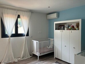 A room with a crib, white wardrobe, and a window with sheer curtains. - Air-conditioned villa for 8 people with a swimming pool – La Crau (LA CRAU)