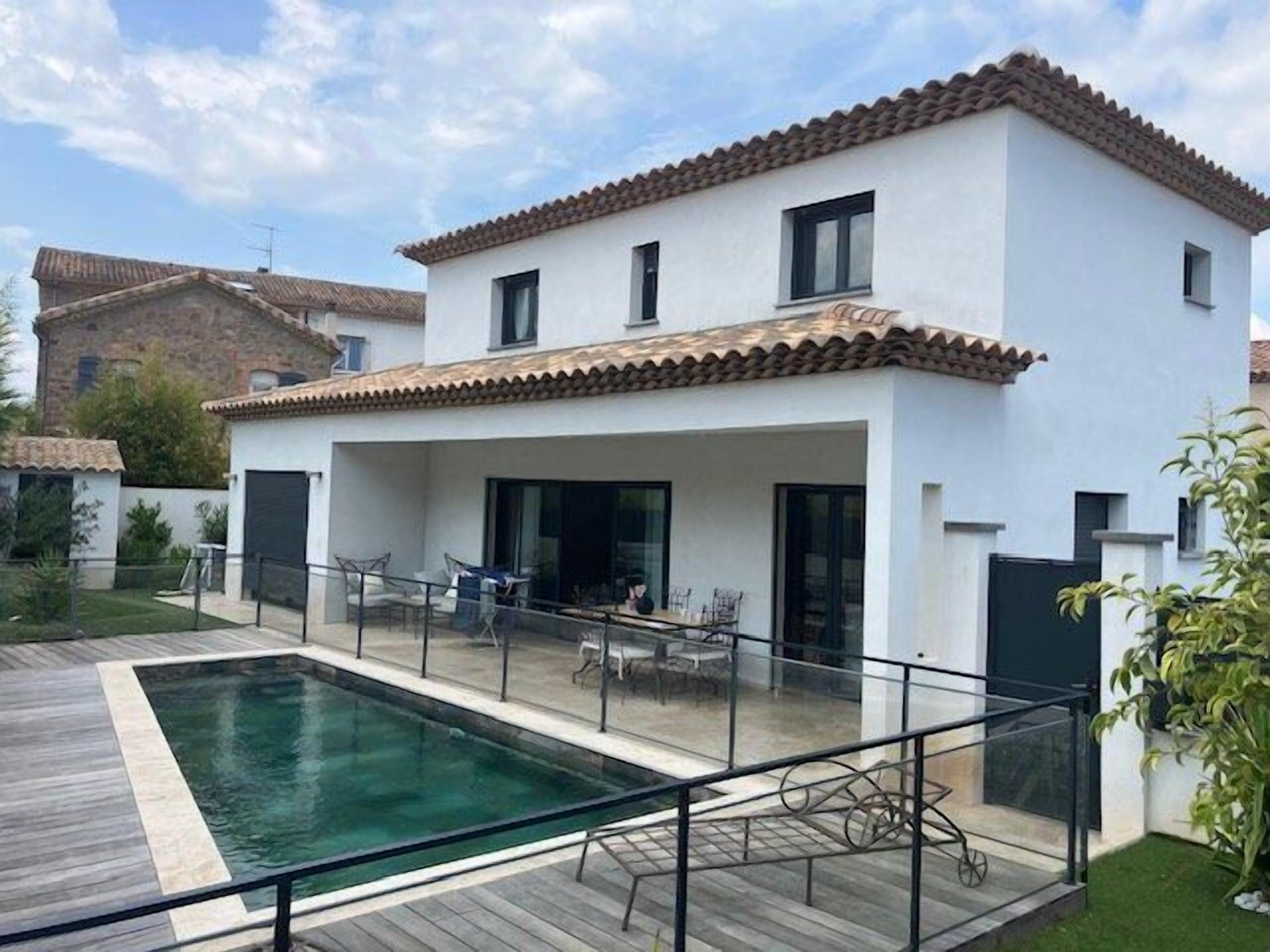 A modern two-story house with a swimming pool, a covered patio, and a fenced yard.