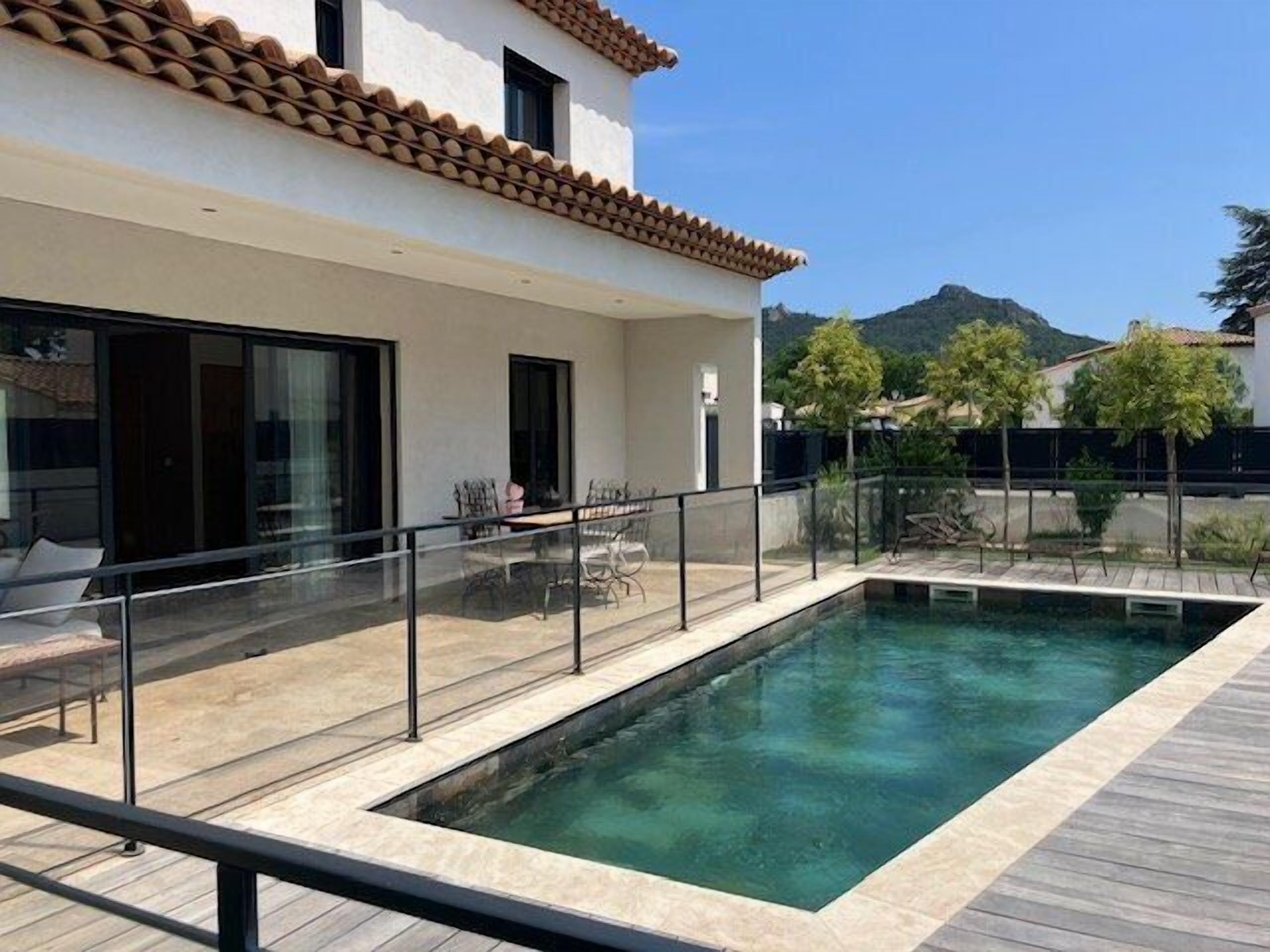 A modern house with a swimming pool, large windows, and a patio area.