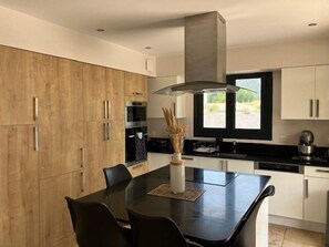 Una cocina moderna con una isla central, sillas negras y una ventana con vistas.