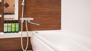 A bathroom with a white bathtub, wooden paneling, and a shelf with green bottles of hair care products. - Ikebukuro Grand Hotel (Tokyo)