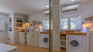 A compact kitchen with built-in appliances, a washing machine, and a dining area.