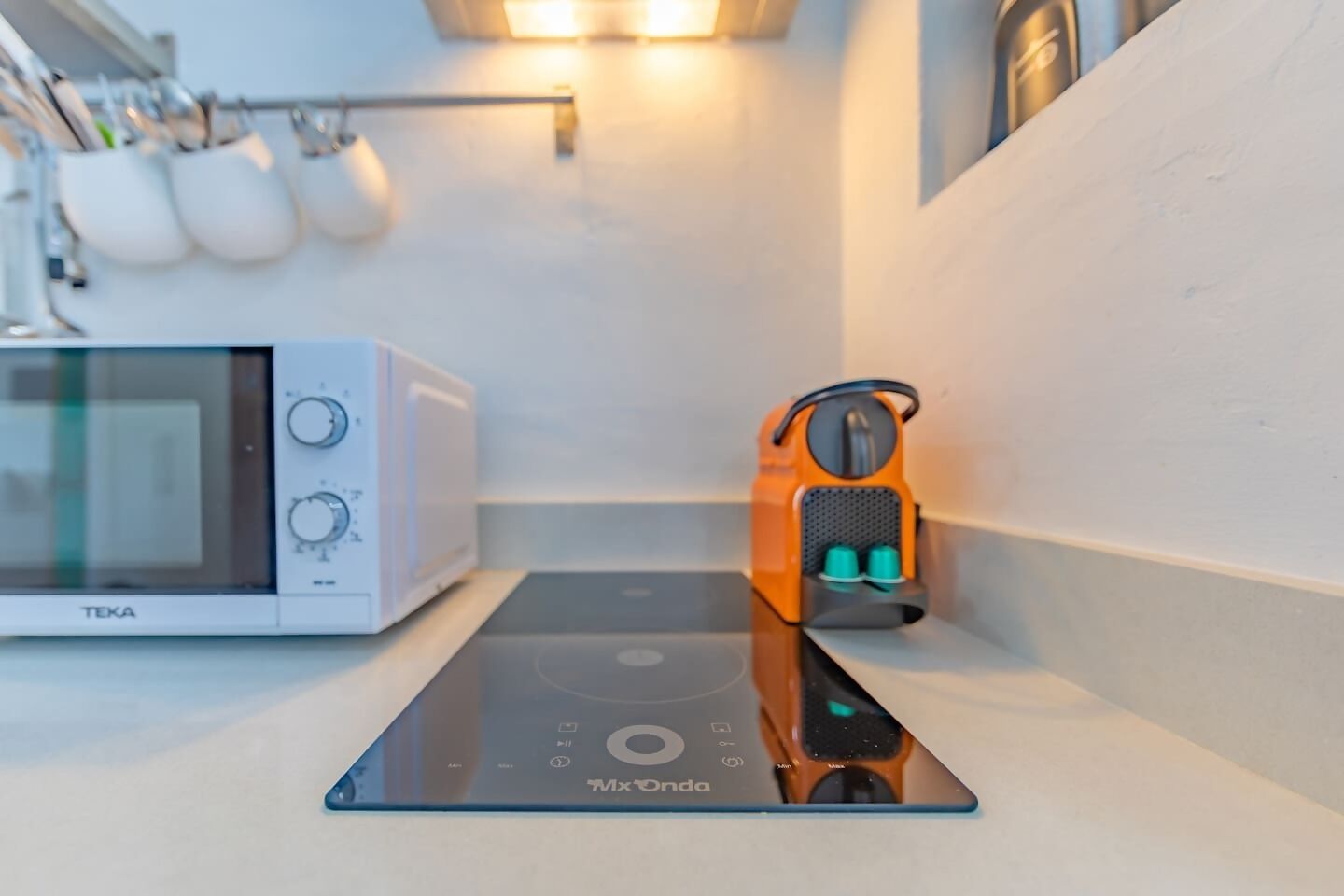 A kitchen with a microwave, a digital scale, and a coffee machine.
