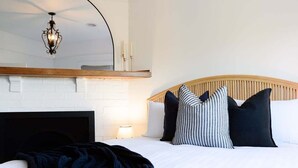 Ein Schlafzimmer mit einem Bett, einem hölzernen Kopfteil, einem Spiegel über dem Bett und einem Wandregal mit Kerzen.