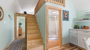 A staircase leading to a second floor, a kitchen with white cabinets, and a framed picture on the wall.