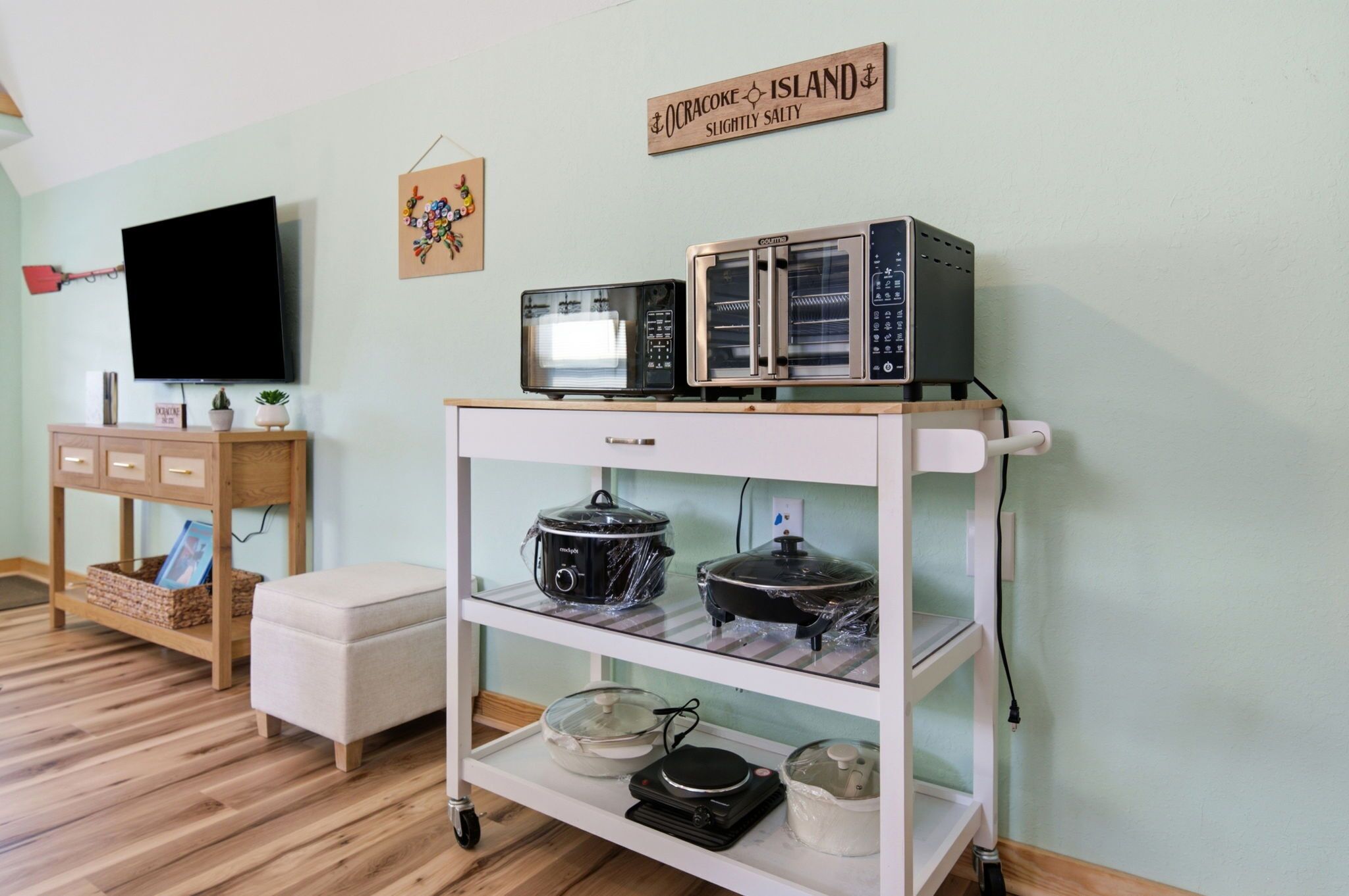 A kitchen with a microwave, oven, and a TV on a stand.
