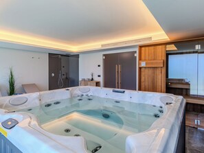 A modern bathroom with a glass-enclosed hot tub, a walk-in shower, and a wooden vanity. - Vacation home Aura by Interhome (Colico)