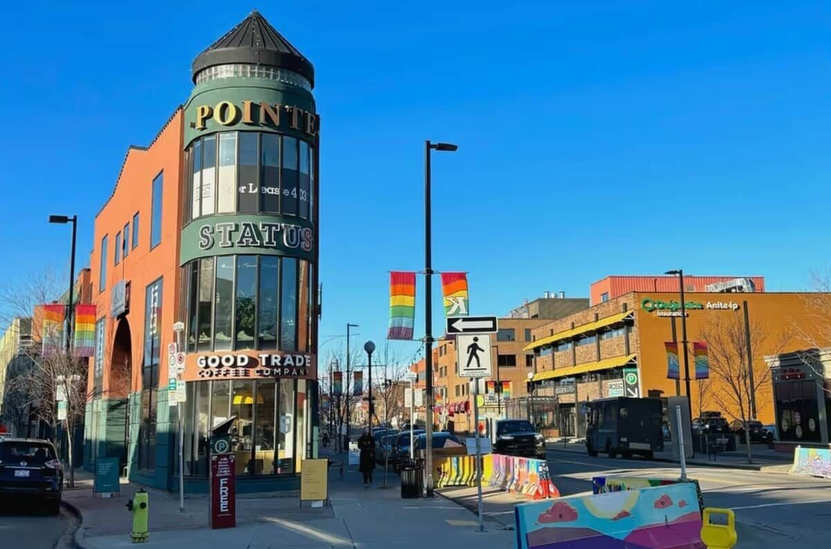 A building with a sign 'POINITE STATUS' and a coffee shop named 'GOOD TRADE COFFEE COMPANY' on the ground floor.