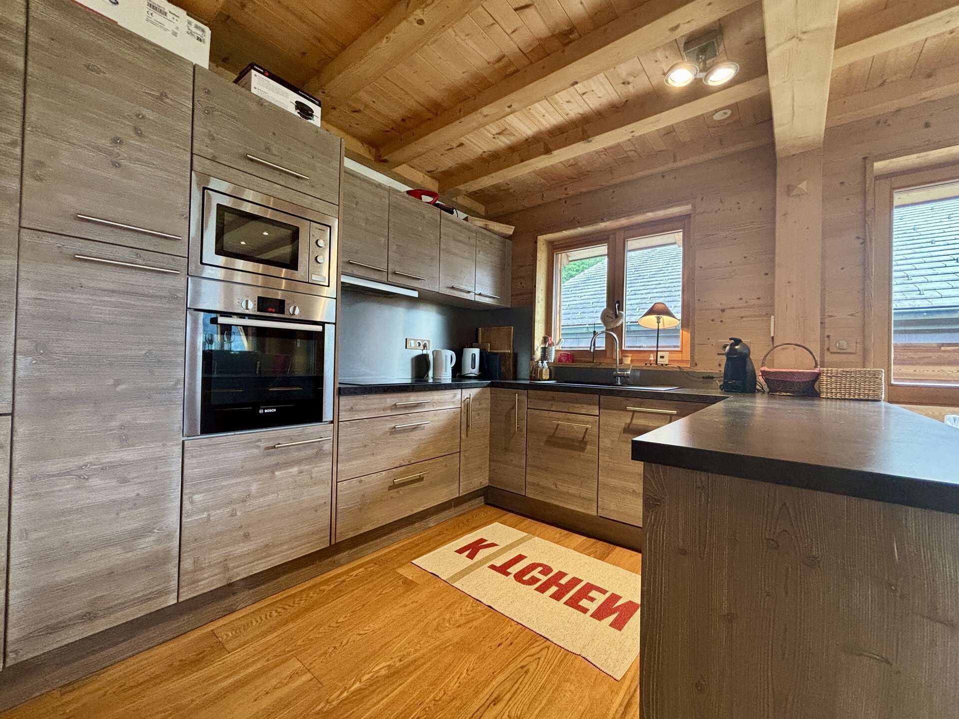 A modern kitchen with wooden cabinets, stainless steel appliances, and a black countertop.