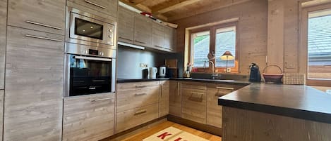 Una cocina moderna con armarios de madera, electrodomésticos de acero inoxidable y encimera negra.