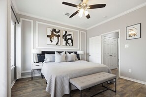 A bedroom with a bed, bedside tables, a ceiling fan, artwork, and a door. - Spacious 3BR, 2.5BA Home - Backyard Patio - Near Downtown Houston (Houston)