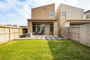 A residential backyard with a patio, a wooden fence, and a house with a flat roof and large windows. - Spacious 3BR, 2.5BA Home - Backyard Patio - Near Downtown Houston (Houston)