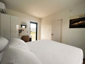 Habitación de hotel con cama, escritorio, silla, armario, puerta y un cartel en la pared.