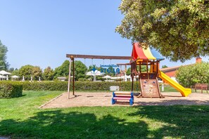 Un'area giochi con altalene, scivolo e angolo arrampicata.