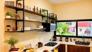 A kitchen with a breakfast setup, shelves with decorative items, a window with a view, and a sink.