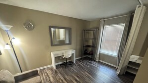 A room with a white desk, a chair, a mirror, a floor lamp, a window with blinds, and a wooden floor. - Spacious & Relaxing 3-bedroom house in Fishers (Fishers)