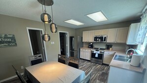 A modern kitchen with a dining area, stainless steel appliances, and pendant lighting. - Spacious & Relaxing 3-bedroom house in Fishers (Fishers)