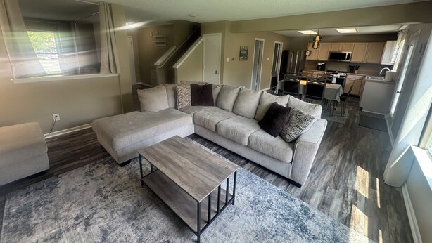 A modern living room with a sectional sofa, a coffee table, and a kitchen in the background. - Spacious & Relaxing 3-bedroom house in Fishers (Fishers)