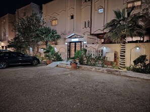 A hotel entrance with a gated driveway, palm trees, and a parked car. - Khair Jewaar Big Ground Apart (Madinah)