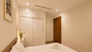 Una habitación de hotel con cama, armario, puerta de madera y un cuadro colgado en la pared.