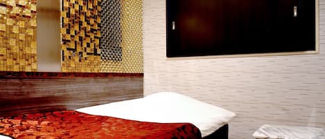 A hotel room with a bed, a window, a wall with a mosaic pattern, and a wooden headboard.