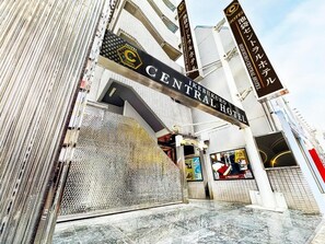 Indgangen til Central Hotel med et markant skilt, et metalhegn og et flisegulv.