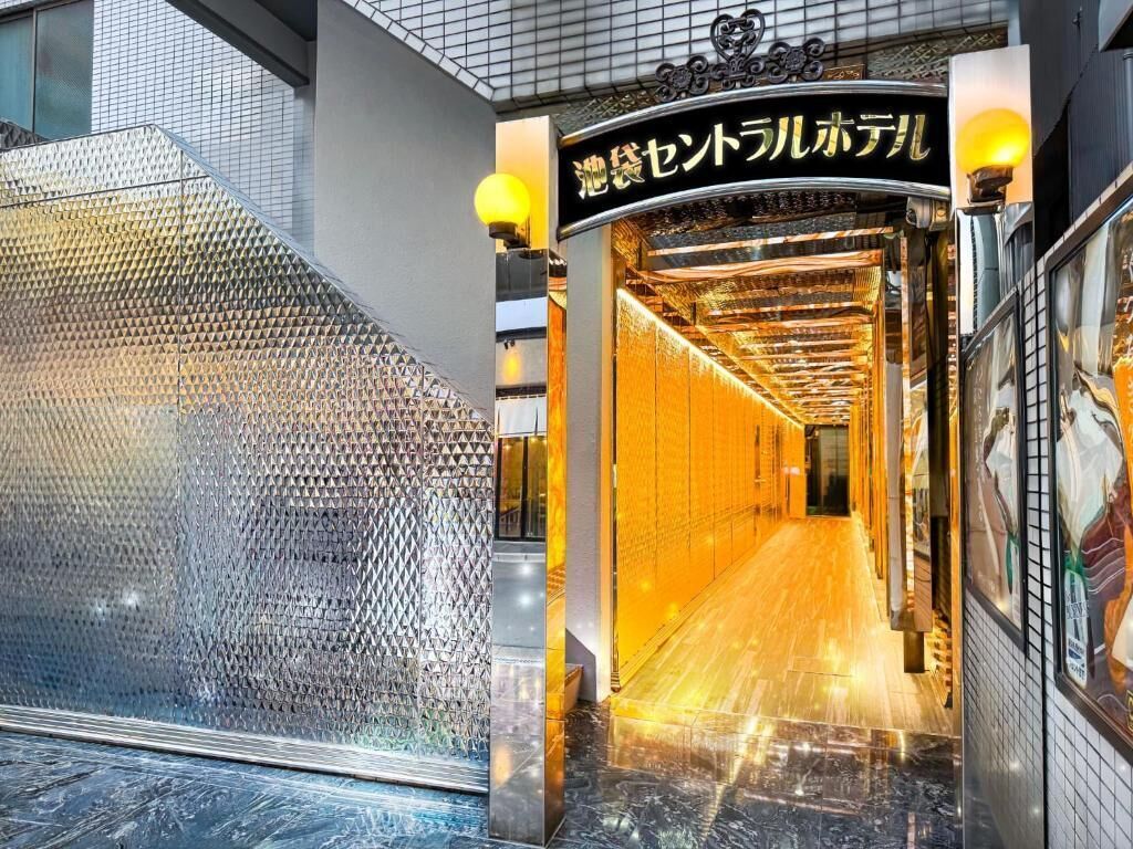 Entrada de hotel con fachada de vidrio, interior dorado y un cartel en idioma extranjero.