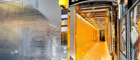 Entrada de hotel con fachada de vidrio, interior dorado y un cartel en idioma extranjero.