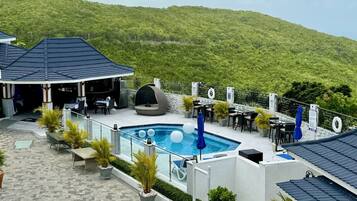 A rooftop pool area with a pool, lounge chairs, and tables.