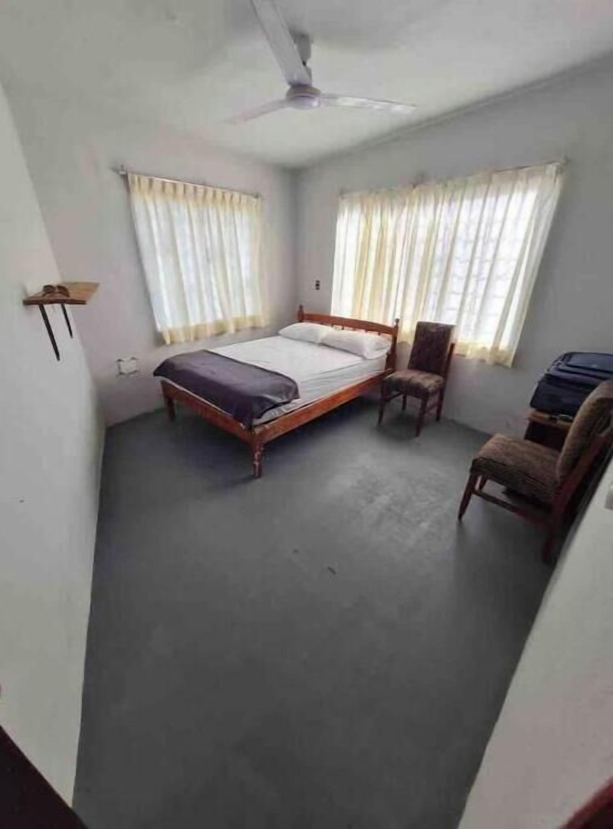 A bedroom with a bed, a chair, a desk, and a ceiling fan.