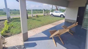A covered outdoor area with a concrete floor, a white pickup truck parked outside, and a wooden chair. - La Poza Country House, near the Costa Esmeralda-10 (Veracruz)