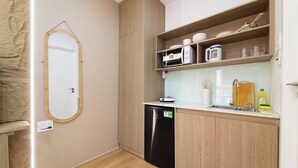 A compact kitchen with a dishwasher, wooden cabinets, a microwave, and a sink. - Double Bedroom With Big Window District 1 (Thành phố Hồ Chí Minh)