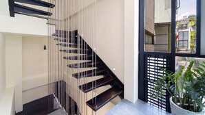 A modern staircase with a glass railing, a potted plant, and a view of the outside. - Double Bedroom With Big Window District 1 (Thành phố Hồ Chí Minh)